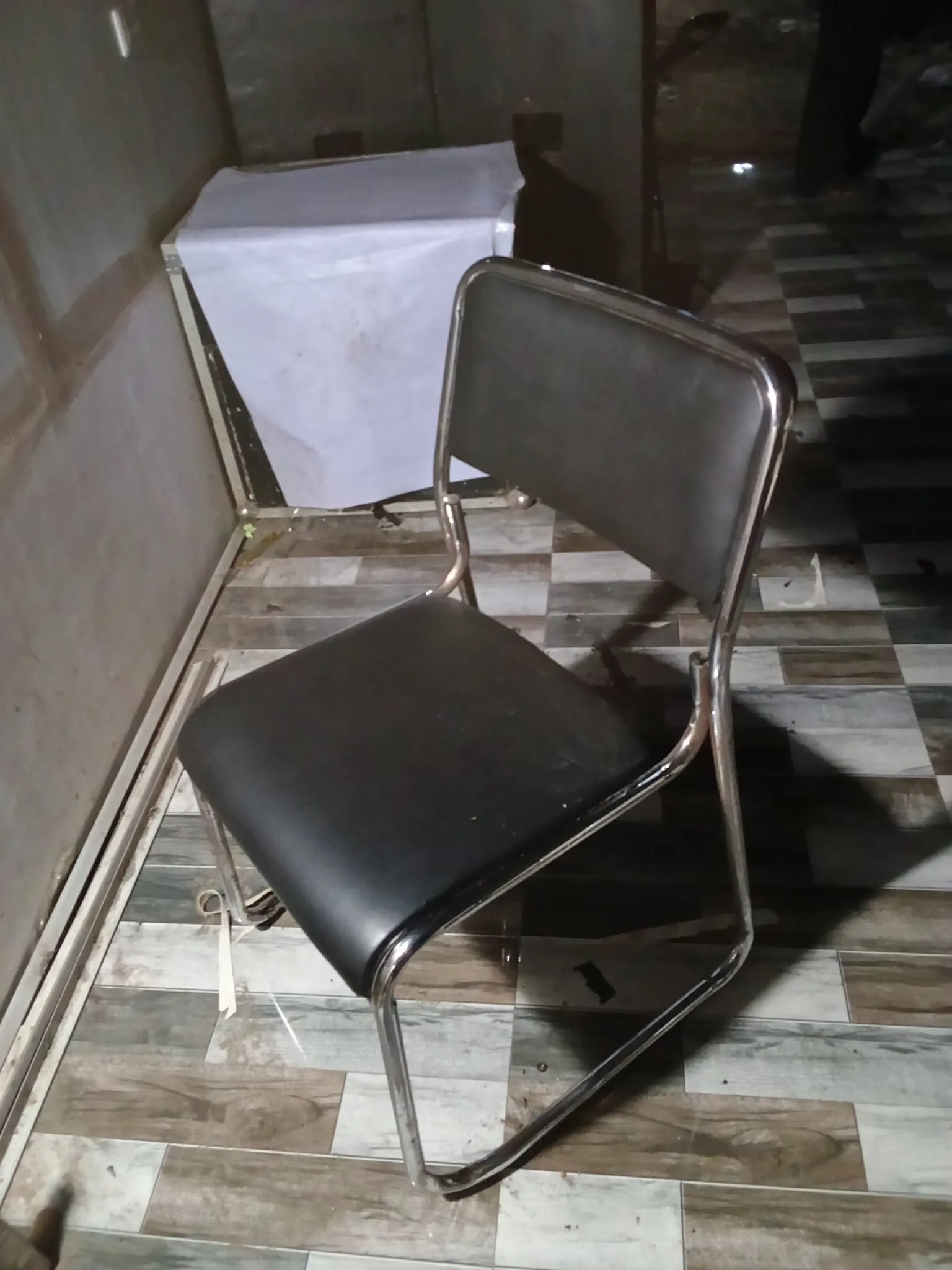  Stacked rows of cream vinyl chairs on bent chrome frames, the sled  bases lined up flush along a tiled floor
