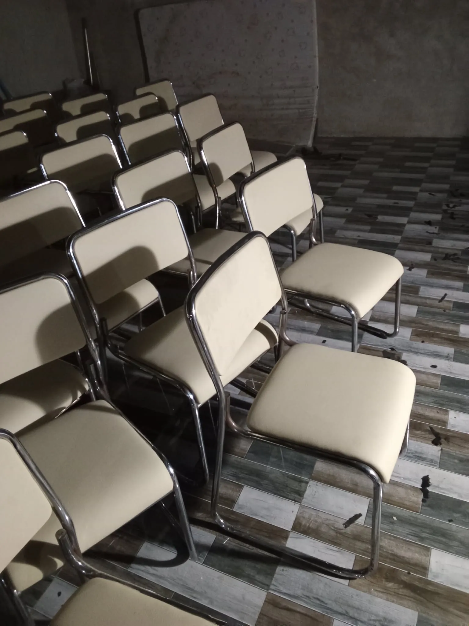 Worn black vinyl seat and back panel on a chrome stacking chair,  scuffed and dulled across the seat