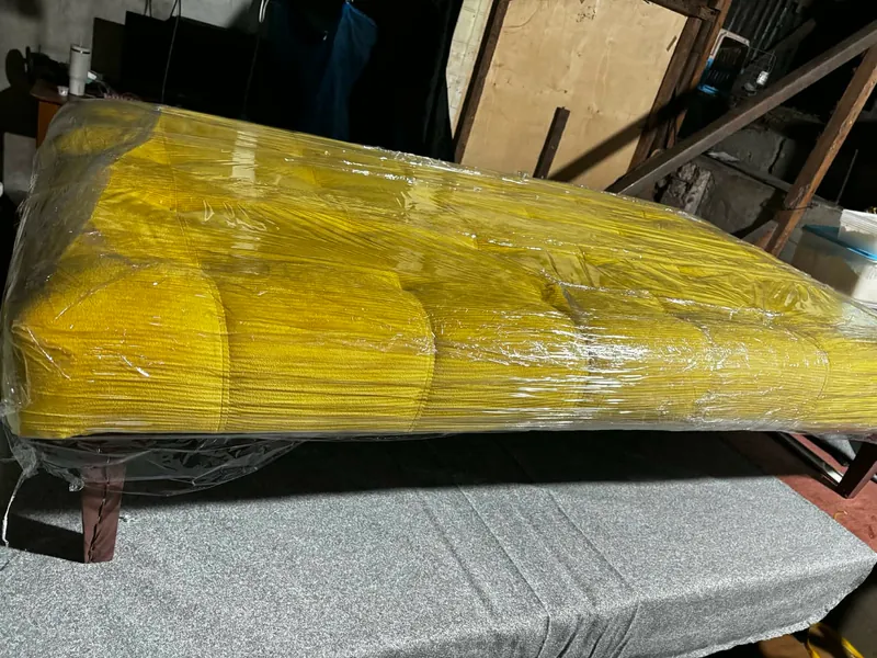 Mustard corduroy sofa bed opened out flat on dark tapered legs, wrapped for delivery in the workshop